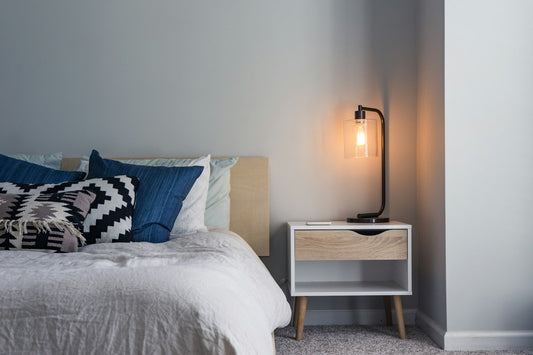 Bedroom nightstand with a black table lamp beside the bed