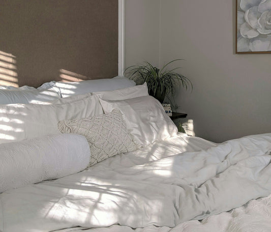 Styled bedroom with white bed linen and a green plant
